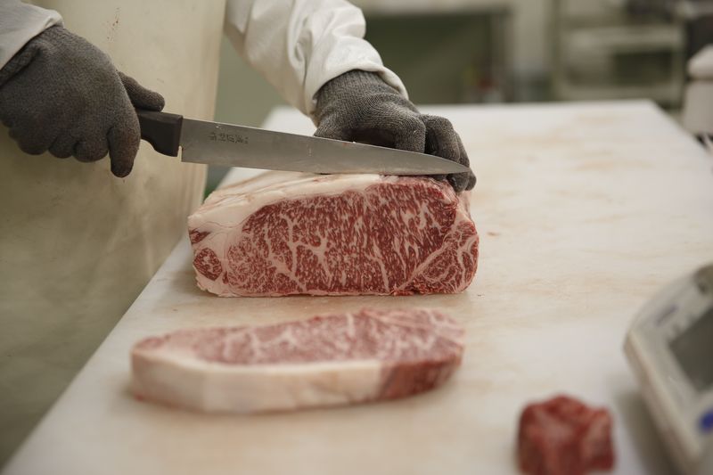 Butcher hand-slicing thick-cut marbled wagyu steaks