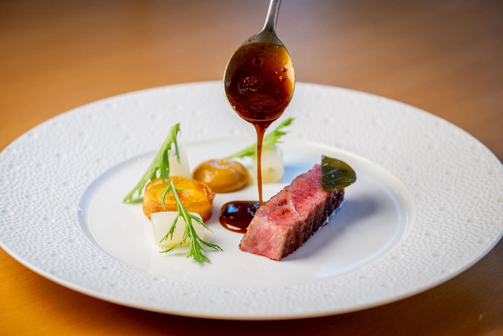 Wagyu steak on a fine-dining plate, sauce poured from a spoon