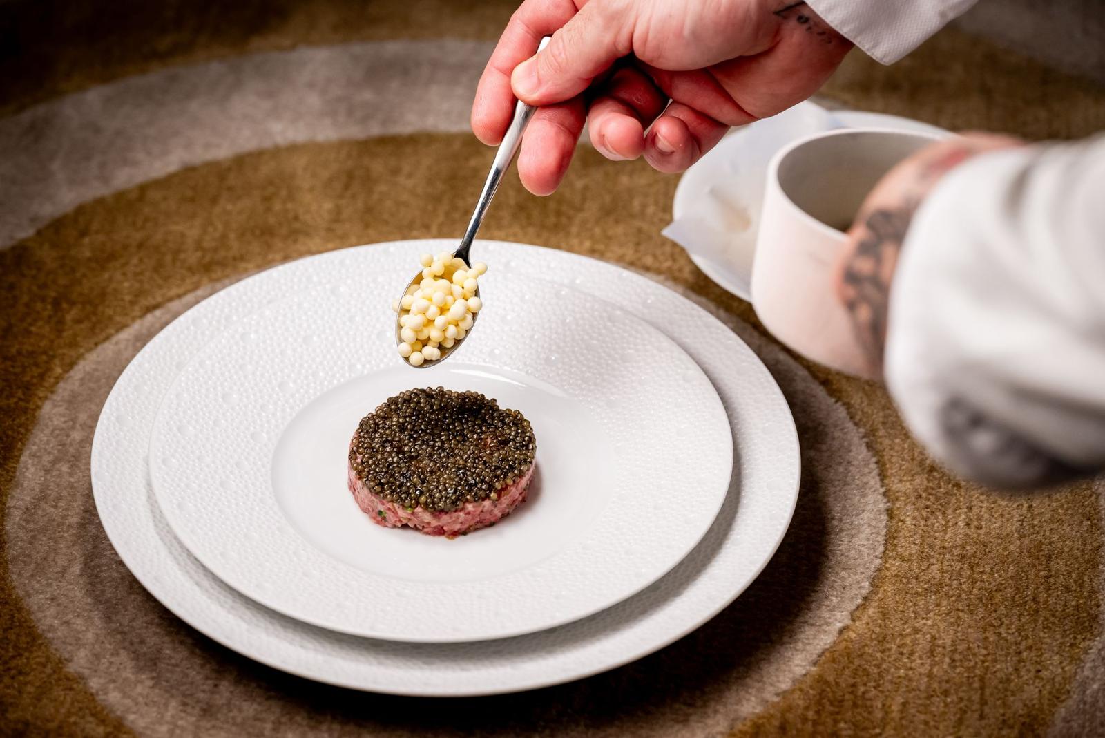 Chef finishing a wagyu tartare with caviar
